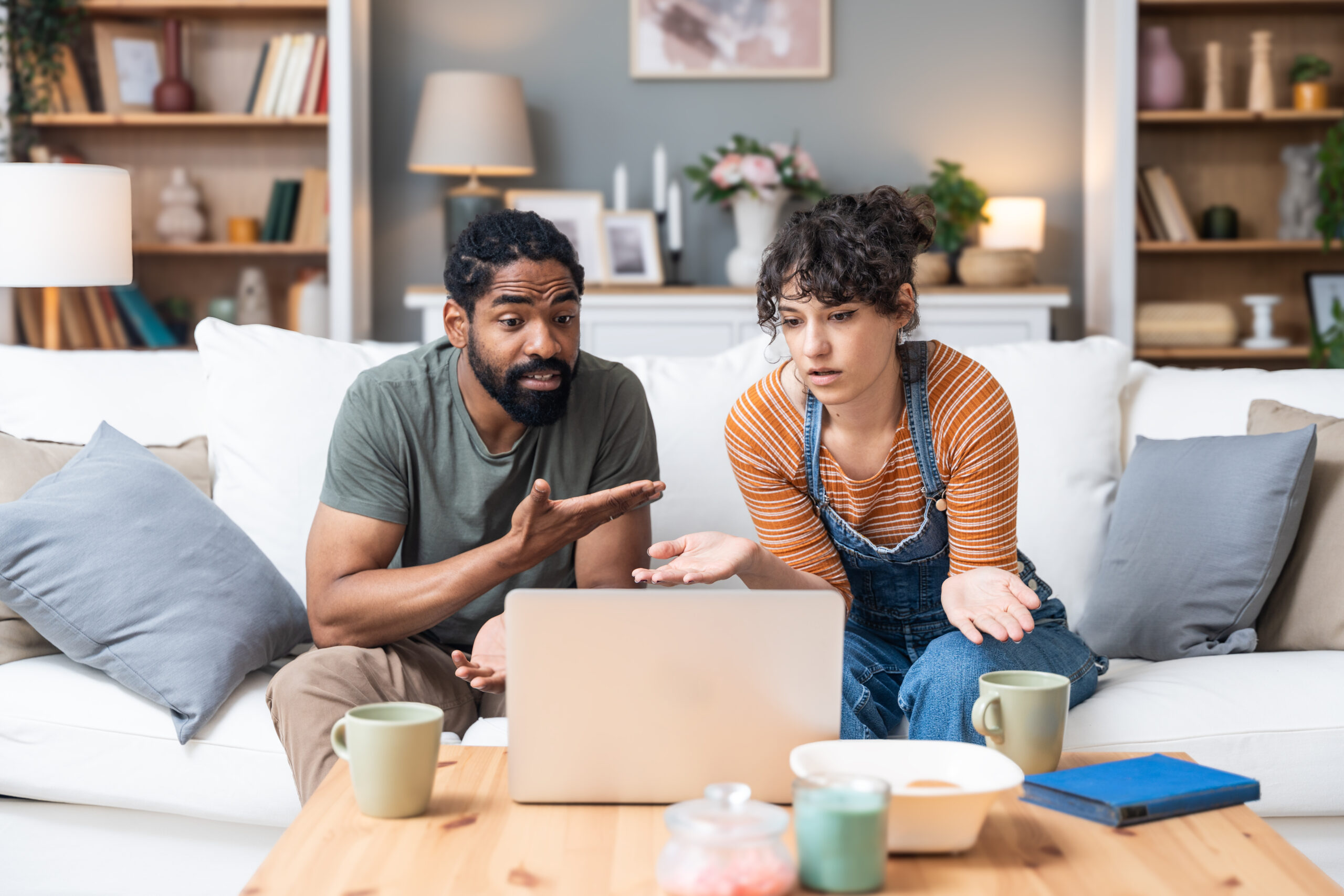 Relationship difficulties, communication problems. Young couple sitting at home having online therapy with psychotherapist on video call on laptop computer. Man and woman talking to therapist.